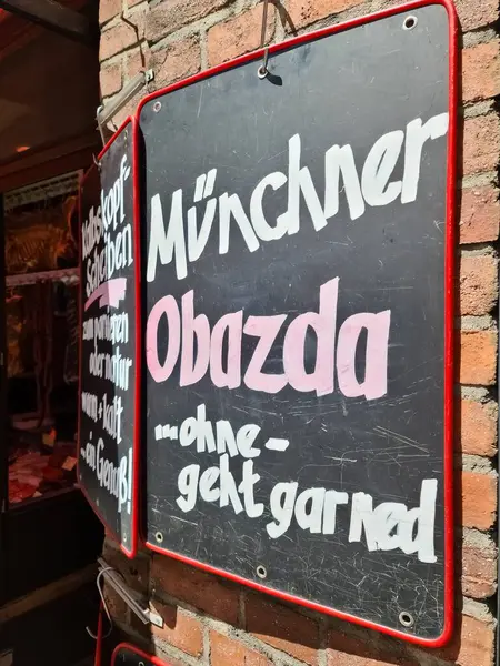 Münih, Almanya - 22. Haziran 2024: Geleneksel bir Bavyera peyniri lezzeti olan Münih obatzda 'yı tanıtan yazı tahtası, yerel mutfağın temel rolünü vurguluyor