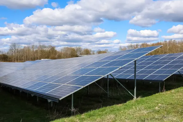 Güneş panellerinin sıraları bir alanda güneş ışığını yakalıyor, bulutlu bir gökyüzünün altında sürdürülebilir elektrik üretiyor