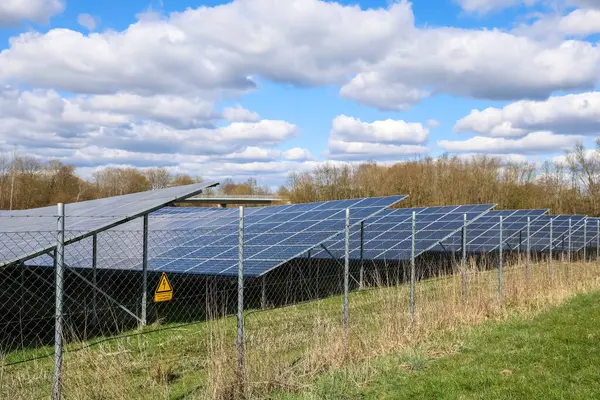 Fotovoltaik paneller güneş parkında elektrik üreterek bulutlu bir gökyüzü altında yenilenebilir enerji üretiyor.