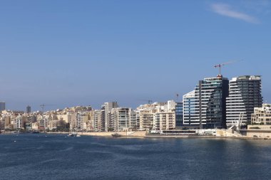 Valletta, Malta 28 Eylül 2024: Modern binalar ve inşaat vinçleri, güneşli bir günde Malta limanının sakin sularına yansıyarak Sliema siluetine hakim oldular