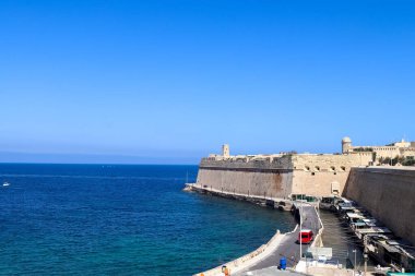 Valletta, Malta 28 Eylül 2024: Valletta, Malta 'daki tarihi Saint Elmo Kalesi' nin panoramik manzarası, açık mavi bir gökyüzü altında kıyı şeridine hakim olan önemli bir dönüm noktası.