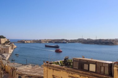 Valletta, Malta 28 Eylül 2024: Kargo gemisi ve feribot Grand Harbour, Valletta, Malta 'da mavi gökyüzüyle güneşli bir günde