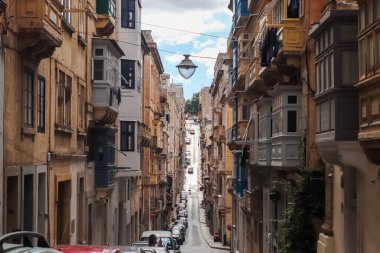 Valletta, Malta - 01. Ekim 2024: Malta 'nın Valletta kentinde dik ve dar bir sokağa bakan geleneksel balkonlar, Yukarı Barrakka Bahçeleri' ne çıkıyor.