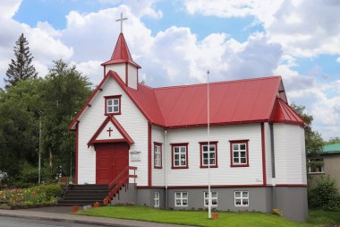 Akureyri, İzlanda - 13. Haziran 2024: Akureyri, İzlanda 'da kırmızı çatılı ve haçlı beyaz ahşap kilise geleneksel İzlanda mimarisini sergiliyor
