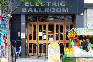 Londra, Birleşik Krallık - 04. Ekim 2024: Londra 'daki Camden Market' te çalışan taze portakal suyu satıcısı ve arka planda Electric Ballroom müzik mekanı