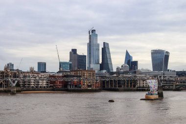Londra, Birleşik Krallık - 04. Ekim 2024: Thames Nehri üzerinde bulutlu bir gökyüzünün altında modern gökdelenlerin yer aldığı Londra 'nın finans bölgesinin panoramik manzarası