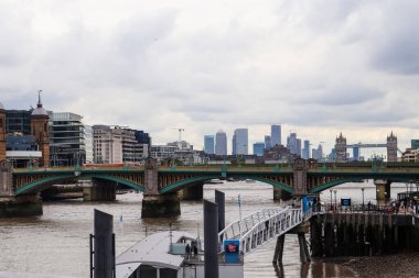 Londra, Birleşik Krallık - 04. Ekim 2024: Thames Nehri üzerindeki Southwark Köprüsü ile Canary Wharf ve Tower Bridge 'in yer aldığı şehir manzarası bulutlu bir gökyüzü altında