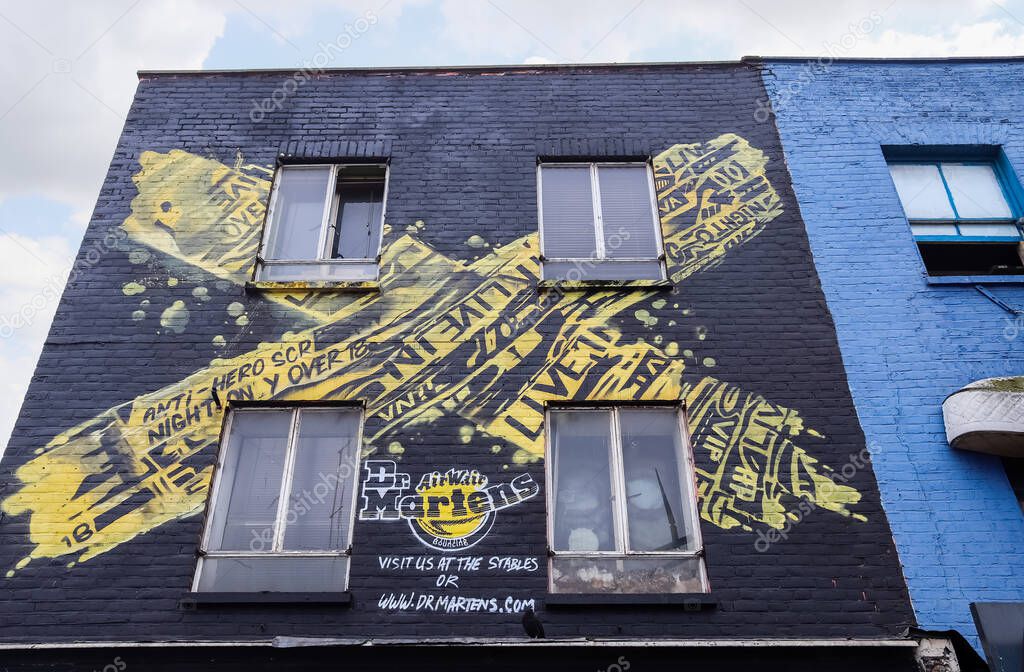 London, United Kingdom - 04. October 2024: Yellow and black Dr Martens advertisement graffiti painted on a brick wall in Camden Town, London