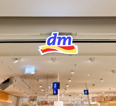 Kiel, Almanya - 19. Nisan 2025: Aydınlatılmış Dm drogerie markt logosu Tavandan sarkan parlak ışıklı bir alışveriş merkezi