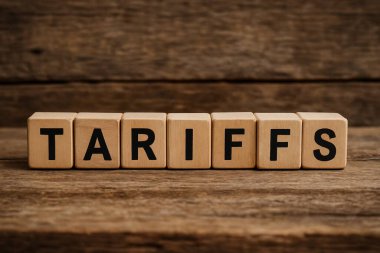 Sözcük tarifeleri ahşap bir masada sıralanmış, görev, vergi ve uluslararası ticaret kavramlarını temsil eden tahtadan küplerde sergileniyor.