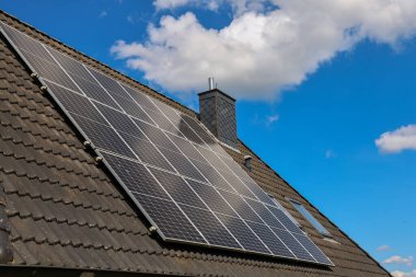 Çatıya monte edilmiş fotovoltaik paneller temiz enerji üretiyor, parlak mavi gökyüzü altında sürdürülebilir bir çözüm sunuyorlar