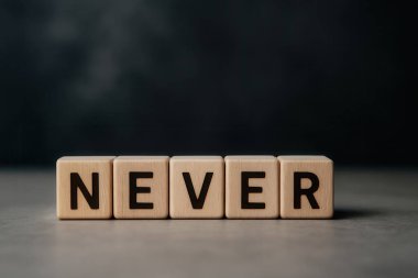 Gri yüzeyde ve koyu arkaplanda olmayan, inkar, reddetme ve olumsuzluk kavramları için mükemmel olmayan dört tahta küp.