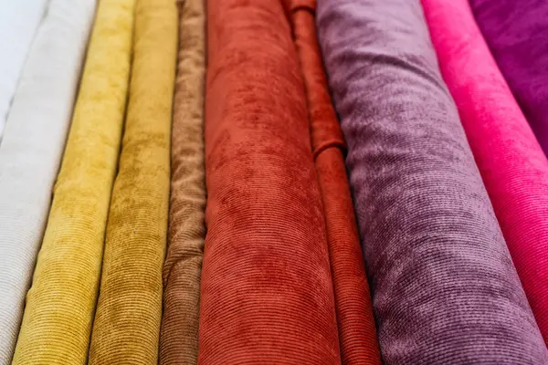 Bir dükkanda çeşitli doku ve renkleri gösteren renkli kadife kumaş ruloları.