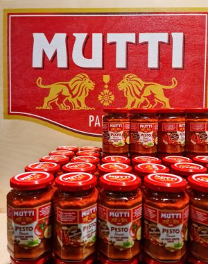 Kiel, Almanya - 05. Mayıs 2025: Mutti pesto rosso kavanozları iki aslanlı büyük bir Mutti logosunun altına istiflenmiş.