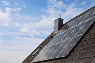 Fotovoltaik paneller, bulutlu bir gökyüzü altında güneş ışığı üreterek sürdürülebilirliği destekleyen fayanslı bir çatıya kurulur.