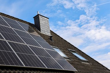 Fotovoltaik paneller, baca ve tavan penceresinin yanı sıra sürdürülebilir ve yeşil enerji sağlayan bir çatıya kurulur.