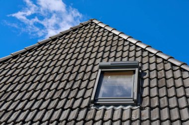 Çağdaş bir evde doğal ışık sağlayan çatı penceresi, açık mavi bir arkaplan ile enerji verimliliğini ve estetiği artırır.