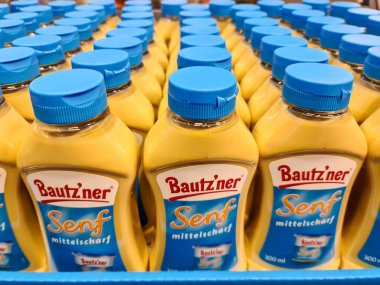 Kiel, Almanya - 28. Mayıs 2025: Orta sıcak Bautz 'ner hardal şişeleri mavi plastik bir sandıkta duruyor, süpermarkette satılmaya hazır.