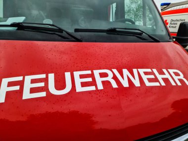 Kiel, Almanya - 28. Mayıs 2025: Üzerinde Feuerwehr ve yağmur damlaları yazan kırmızı bir itfaiye aracının yakın çekimi