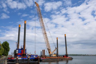 Kiel, Almanya - 28. Mayıs 2025: Turna bir mavnada çalışıyor, Almanya 'nın Kiel kentinde açık deniz inşaat çalışmaları yapıyor.