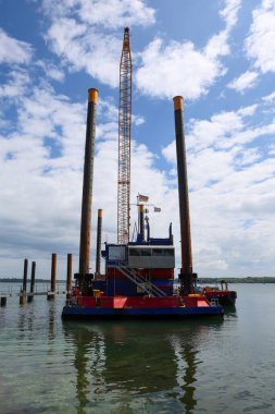 Kiel, Almanya - 28. Mayıs 2025: Turna ve kazık mavnası Almanya 'da bulutlu gökyüzünün altında Kiel' in rıhtımında çalışıyor