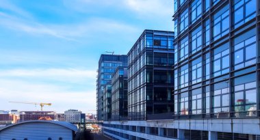 Almanya 'da Kiel' de bulunan pencerelere cam ve güneş ışığı yansıtan modern ofis cepheleri.