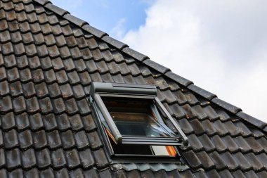 Kiremit kaplı bir çatıda açık çatı penceresi, doğal ışık ve temiz havanın boşluğu doldurmasına izin vererek, evin havalandırmasını ve tasarımını artırır.