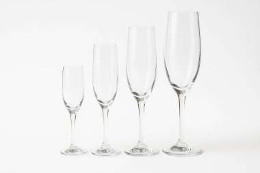 Beyaz arka planda kadehler giderek büyüyen dört boş şampanya kadehi kutlama için bir çeşitlilik ve seçim hissi yaratıyor.