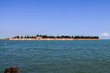 Venedik, İtalya - 24 Mayıs 2024: San Michele adasının antik anıtsal mezarlığı, bitki örtüsü ve kırmızı tuğla duvarları ile Venedik lagünüyle çevrilidir.