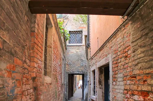 Venedik, İtalya - 24 Mayıs 2024: Tuğla duvarlı dar geçit ve Venedik, İtalya 'da başka bir sokağa açılan kemer yolu