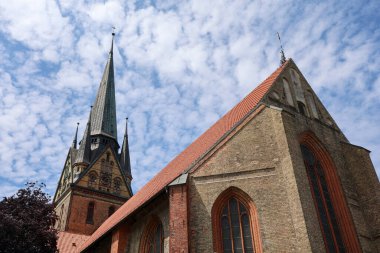 Flensburg, Almanya - 13. Haziran 2025: Majestic Marienkirche Flensburg 'da mavi gökyüzü ve beyaz bulutların önünde dimdik ayakta duruyor