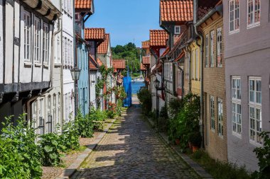 Flensburg, Almanya - 13. Haziran 2025: Almanya 'daki Flensburg limanına uzanan renkli evleri olan Dar Sokak