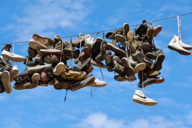 Flensburg, Almanya - 13. Haziran 2025: Flensburg 'da bir kablodan sarkan spor ayakkabıları, açık mavi gökyüzünün arka planına karşı eşsiz bir görüntü yaratıyor