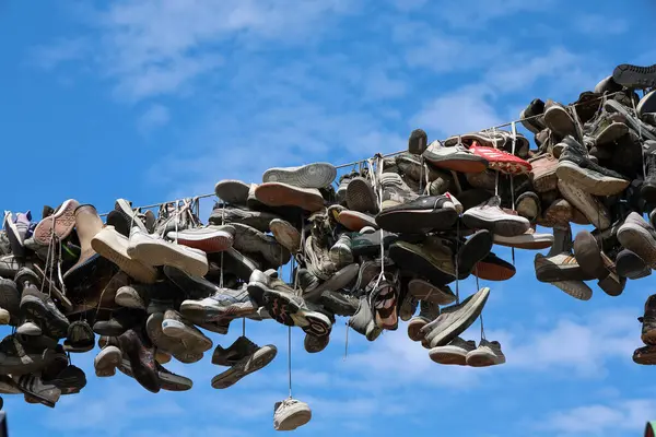 Flensburg, Almanya - 13. Haziran 2025: Bir kablodan sarkan ayakkabılar Almanya 'nın Flensburg kentinde canlı bir mavi gökyüzüne karşı eşsiz bir görüntü oluşturuyor