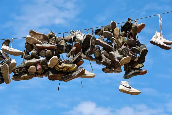 Flensburg, Almanya - 13. Haziran 2025: Flensburg 'da bir kablodan sarkan spor ayakkabıları, açık mavi gökyüzünün arka planına karşı eşsiz bir görüntü yaratıyor