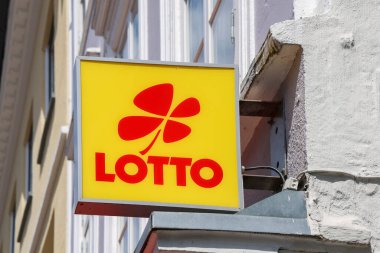 Flensburg, Almanya - 13. Haziran 2025: Flensburg, Almanya 'da bir binaya asılmış dört yapraklı kırmızı bir yonca ve logo içeren sarı Lotto işareti, şans simgesi.