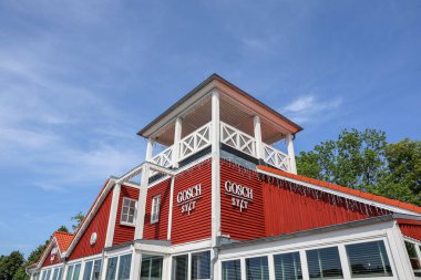 Flensburg, Almanya - 13. Haziran 2025: Almanya 'nın Flensburg kentindeki Gosch Sylt restoranında çarpıcı bir kırmızı cephe ve şehir manzarasını geliştiren büyüleyici bir beyaz gözlem kulesi bulunmaktadır.