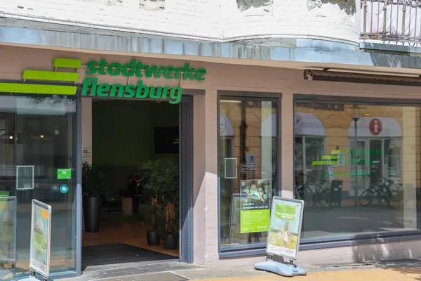 Flensburg, Almanya - 13. Haziran 2025: Almanya 'nın Flensburg kentinde güneşli bir yaz gününde yeşil logolu Stadtwerke Flensburg ofis binasının ön manzarası