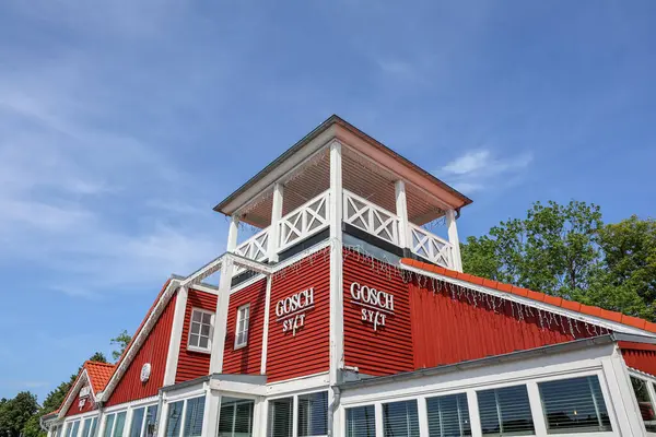 Flensburg, Almanya - 13. Haziran 2025: Almanya 'nın Flensburg kentindeki Gosch Sylt restoranında çarpıcı bir kırmızı cephe ve şehir manzarasını geliştiren büyüleyici bir beyaz gözlem kulesi bulunmaktadır.