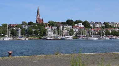 Flensburg, Almanya 'nın şehri, açık mavi gökyüzü altında tekneleri ve önemli kiliseleri barındırıyor.