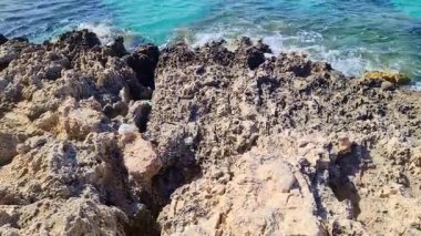 Turkuaz Akdeniz suları engebeli Malta kıyı şeridinde çağlayarak parlak yaz güneşi altında doğal kayalık kıyı şeridi manzaralı güzelliği gözler önüne seriyor.