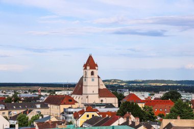 Eisenstadt, Avusturya - 12. Temmuz 2025: Stadtpfarrkirche Kilisesi, Avusturya 'nın Eisenstadt kentinde, kırmızı çatılar ve sakin bir manzarayla çevrili olarak ayakta duruyor.