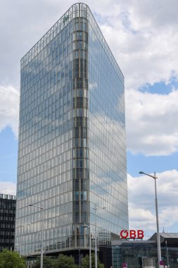 Viyana, Avusturya - 12. Temmuz 2025: Bulutlu bir günde Avusturya 'nın Viyana kentindeki OBB genel merkezi yakınlarında bulutları yansıtan modern cam gökdelen