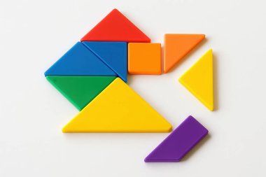 Renkli tangram yapbozu, beyaz bir arkaplana yerleştirilmiş bazı eksik parçalarla neredeyse tamamlandı, problem çözme ve yaratıcı düşünceyi temsil ediyor.