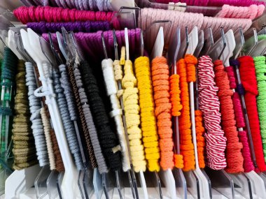 Bir tuhafiyede asılı renkli kabloların görüntülenmesi, dikiş ve el işi projeleri için geniş bir seçim sunar