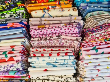 Çok sayıda renkli desenli kumaş yığını çeşitli tasarımları, dokuları ve renkleri, ilham verici tekstil meraklıları ve tasarımcıları sergiliyor.