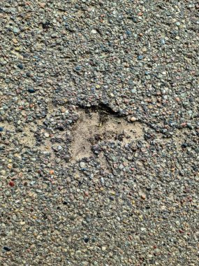 Hasarlı asfalt görüntüsünü kapatın. Altında çakıl ve kir var. Soyut bir kalıp oluşturuyor.