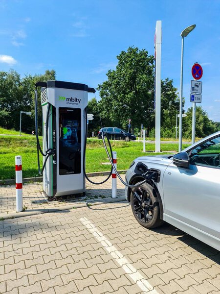 Мбаппе, Германия - 09. Август 2025: Современный электромобиль, подключенный к пункту зарядки на общественной зарядной станции, способствующий устойчивому транспорту