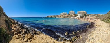 Golden Beach, Malta - 30. Eylül 2024: Kristal berrak suların ve Golden Bay 'deki kumlu plajın keyfini çıkaran turistlerin panoramik manzarası