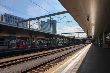 Viyana, Avusturya - 10. Temmuz 2025: Güneşli bir günde arka planda modern binalar bulunan Viyana Merkez İstasyonu 'ndaki boş platformlar